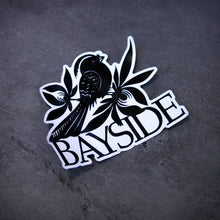Load image into Gallery viewer, image of a sticker that is a bird and says bayside. laid flat on a concrete floor
