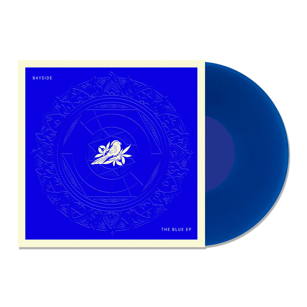 A transparent blue vinyl record slides out of a deep blue, white-bordered cover featuring a white rose and intricate circles. Text on the square sleeve reads 
