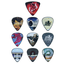 Load image into Gallery viewer, Nine Bayside guitar picks, each featuring unique images, abstract patterns, and band logos, are arranged in a 3x3 grid next to a sleek metal case, offering both stylish design and secure storage.