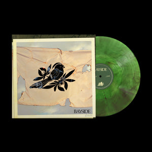 A green marbled vinyl of Baysides The Walking Wounded rests by its album cover, which shows a black bird and flowers on worn beige fabric. Bayside appears in the bottom right corner with tracklist details.