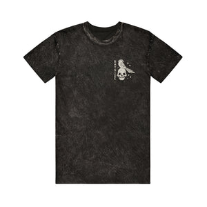 image of the front of a black mineral wash tee shirt on a white background. tee has a small chest print in white of a skull head and a bird. 
