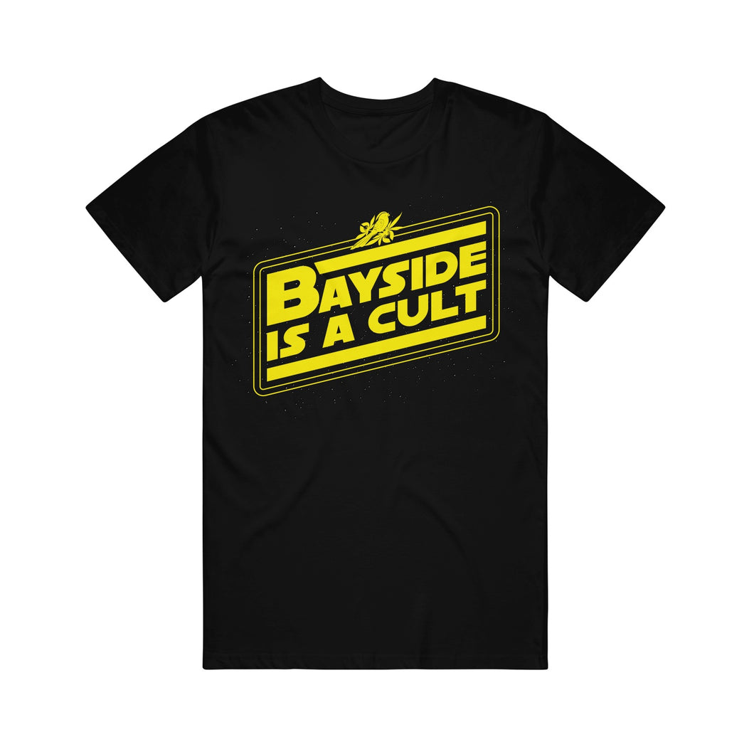 black tee shirt on a white background. There is a full chest print in yellow that is slanted and has a bird on top and says Bayside is a cult inside an angled rectangle. 