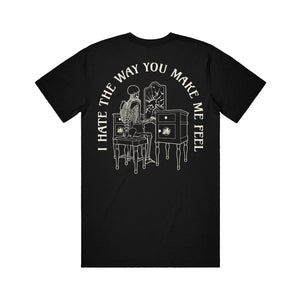 image of the back of a black tee shirt on a white background. tee has a print of a person looking in a broken mirror of a vanity. arched around says i hate the way you make me feel.
