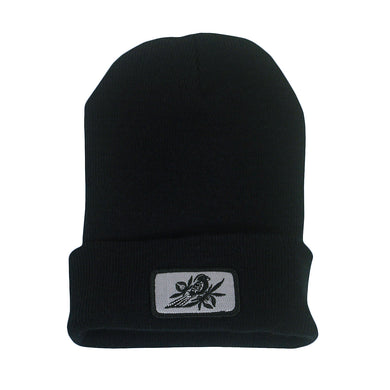 image of a black winter beanie on a white background. beanie has sewn on rectangle patch on the front cuff. patch is grey with a bird in black