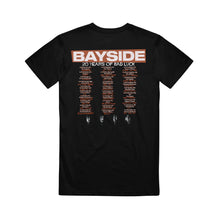 Load image into Gallery viewer, image of the back of a black tee shirt on a white background. there is a full back print in orange and cream that says at the top bayside 20 years of bad luck with a three row stacked list of cancelled tour dates.