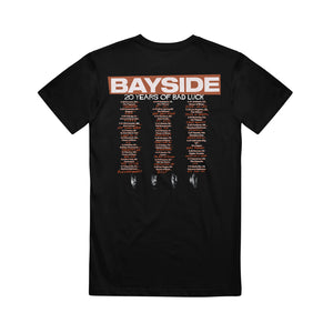 image of the back of a black tee shirt on a white background. there is a full back print in orange and cream that says at the top bayside 20 years of bad luck with a three row stacked list of cancelled tour dates.