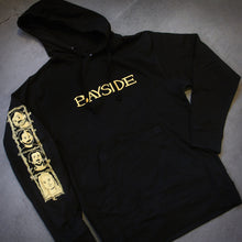 Load image into Gallery viewer, image of the front of a black pullover hoodie laid flat on a concrete floor. front of hoodie says bayside across the chest and has a left sleeve print. 