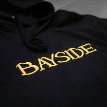 Load image into Gallery viewer, close up image of the  front of a black hoodie that says bayside across the chest in puff printing