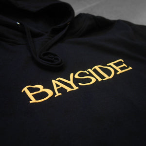 close up image of the  front of a black hoodie that says bayside across the chest in puff printing