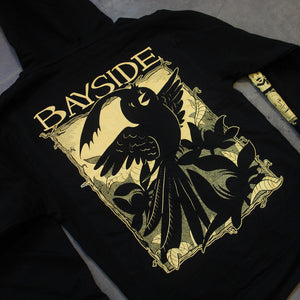 image of the back of a black pullover hoodie laid flat on a concrete floor. back of hoodie has a full back print of a cartoon bird