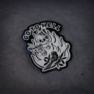 image of a sticker that says go to hell and has a skeleton smoking a joint and the bird on it. laid flat on a concrete floor