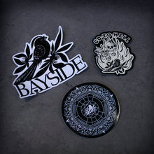 Load image into Gallery viewer, image of three stickers laid on a concrete floor. top sticker is a bird and says bayside. bottom sticker is a circle with a mandella and a bird design. the right sticker says go to hell and has a skeleton smoking a joint and the bird on it.