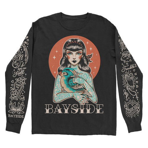 image of a black long sleeve tee shirt on a white background. tee has full body print of a girl with tattoos all over holding a bird. across the bottom says Bayside. each sleeve has tattoo flash art